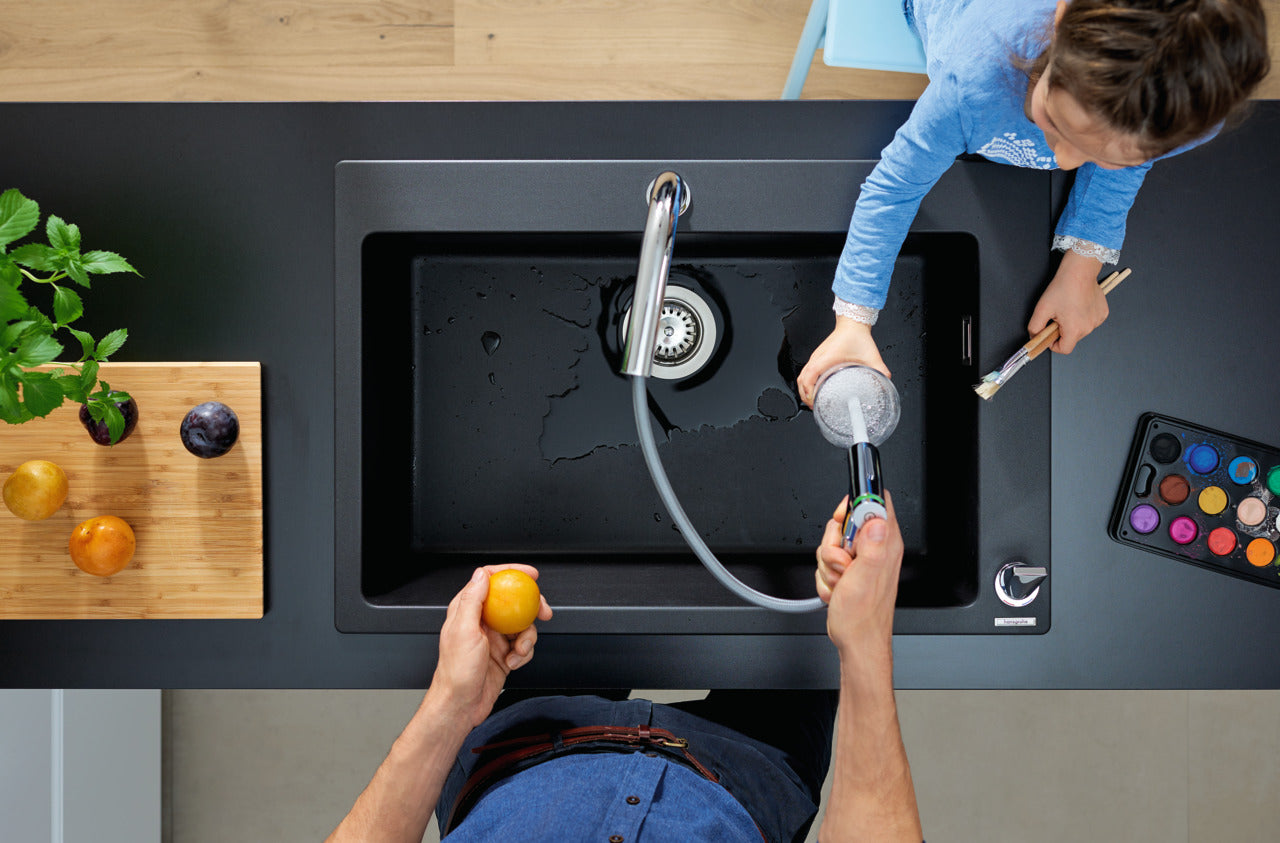 man filling cup with hansgrohe kitchen sink mixer with pull out spray