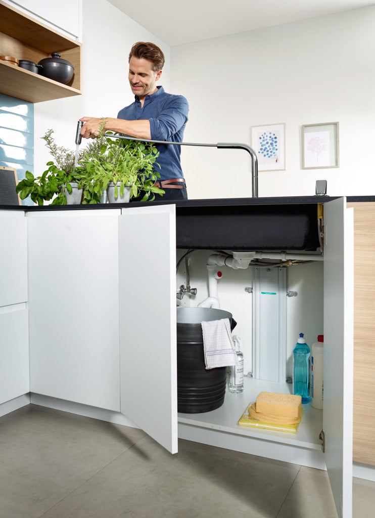 man watering plants with hansgrohe kitchen sink mixer with pull out spray